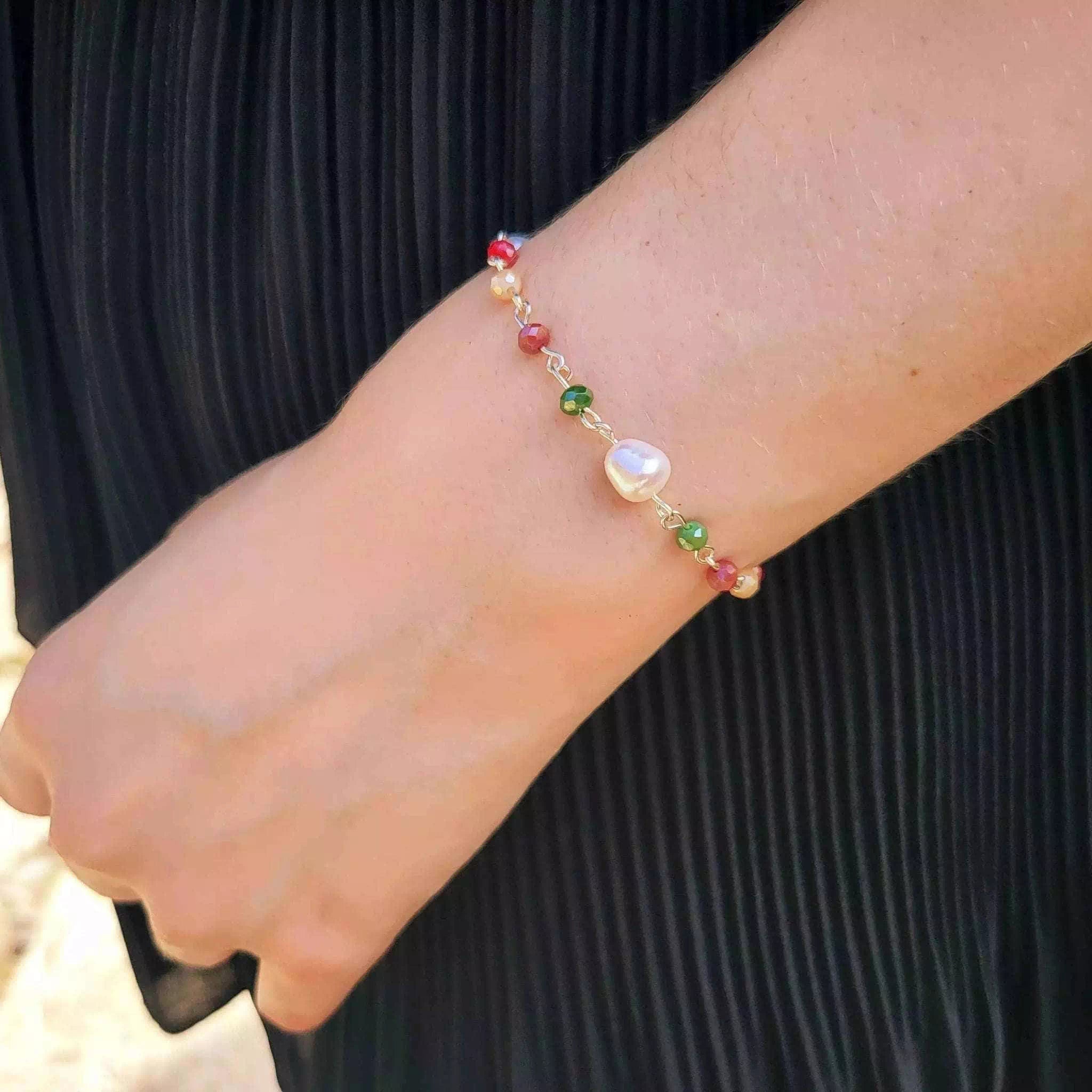 Bracelet en plaqué argent et perles multicolores porté au poignet d'une femme.