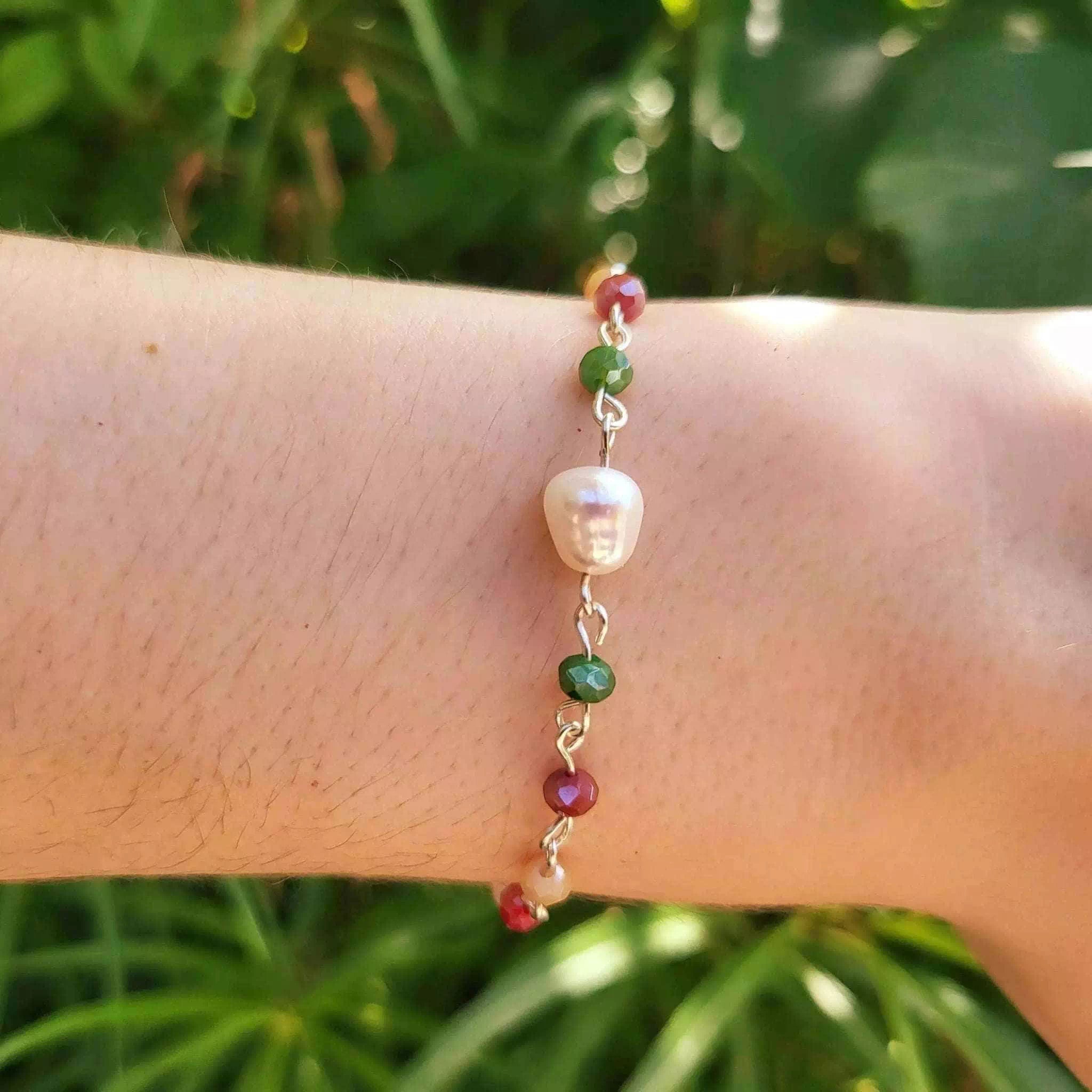 Gros plan sur les détails des cristaux facettés multicolores et de la véritable perle d'eau douce du bracelet Jethyka.