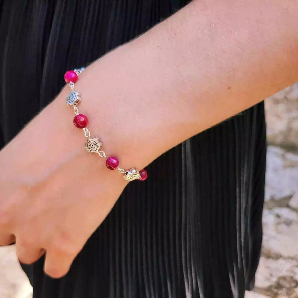 Bracelet pour femme ajustable en acier ou métal argenté avec perles rondes roses, porté délicatement au poignet.