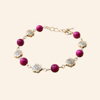Bracelet de créateur avec perles en pierre naturelle œil de tigre rose et intercalaires roses en métal argenté, présenté sur un fond uni beige clair.