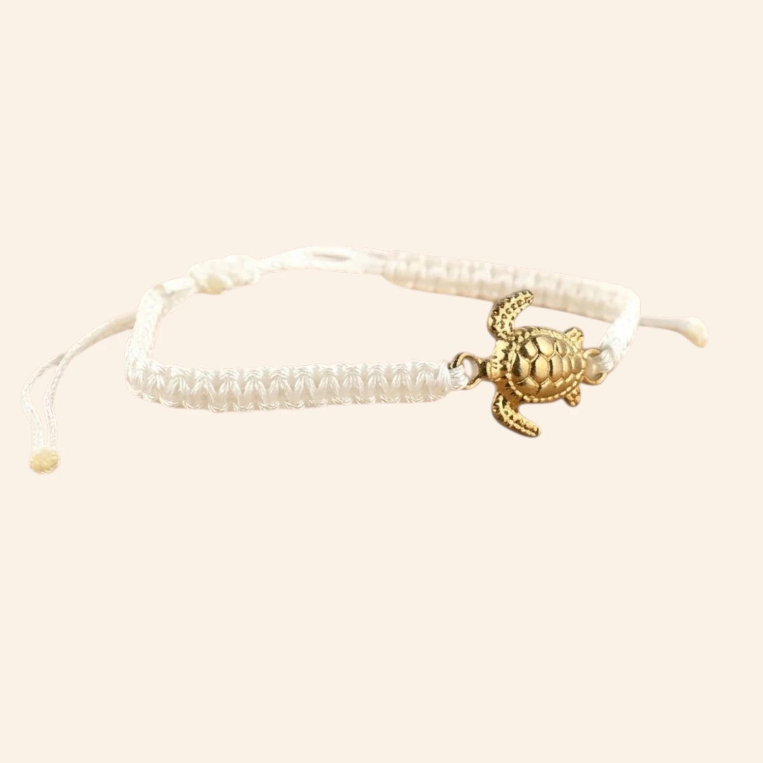 Vue de trois-quarts droit du bracelet ajustable blanc avec son motif tortue marine dorée.