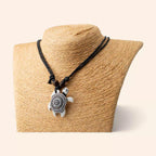 Collier tortue blanche style ethnique avec motifs mandala noirs présenté de face sur un buste de mannequin beige.