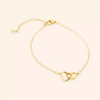 Bracelet JETHYKA doré avec deux cœurs entrelacés, chaîne fine réglable, bijou symbolique et élégant.