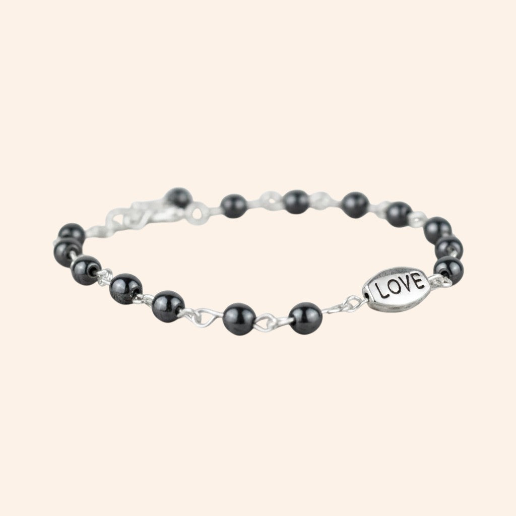 Bracelet JETHYKA Love en hématite naturelle, perles grises et breloque argentée, bijou élégant et énergétique.